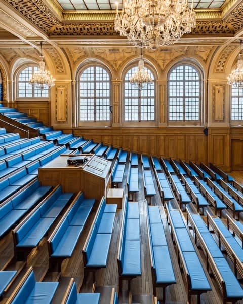 Le grand amphithéâtre de la Maison de l’Océan, ses gradins de bois et ses banquettes bleues sous les lustres de cristal.