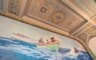 Un plafond à caissons peints et dorés surplombant une fresque marine où des marins rament dans une baleinière verte.