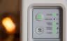Le panneau de voyants d’un routeur, bouton Wi-Fi et voyants verts allumés, à côté d’une flamme floue.