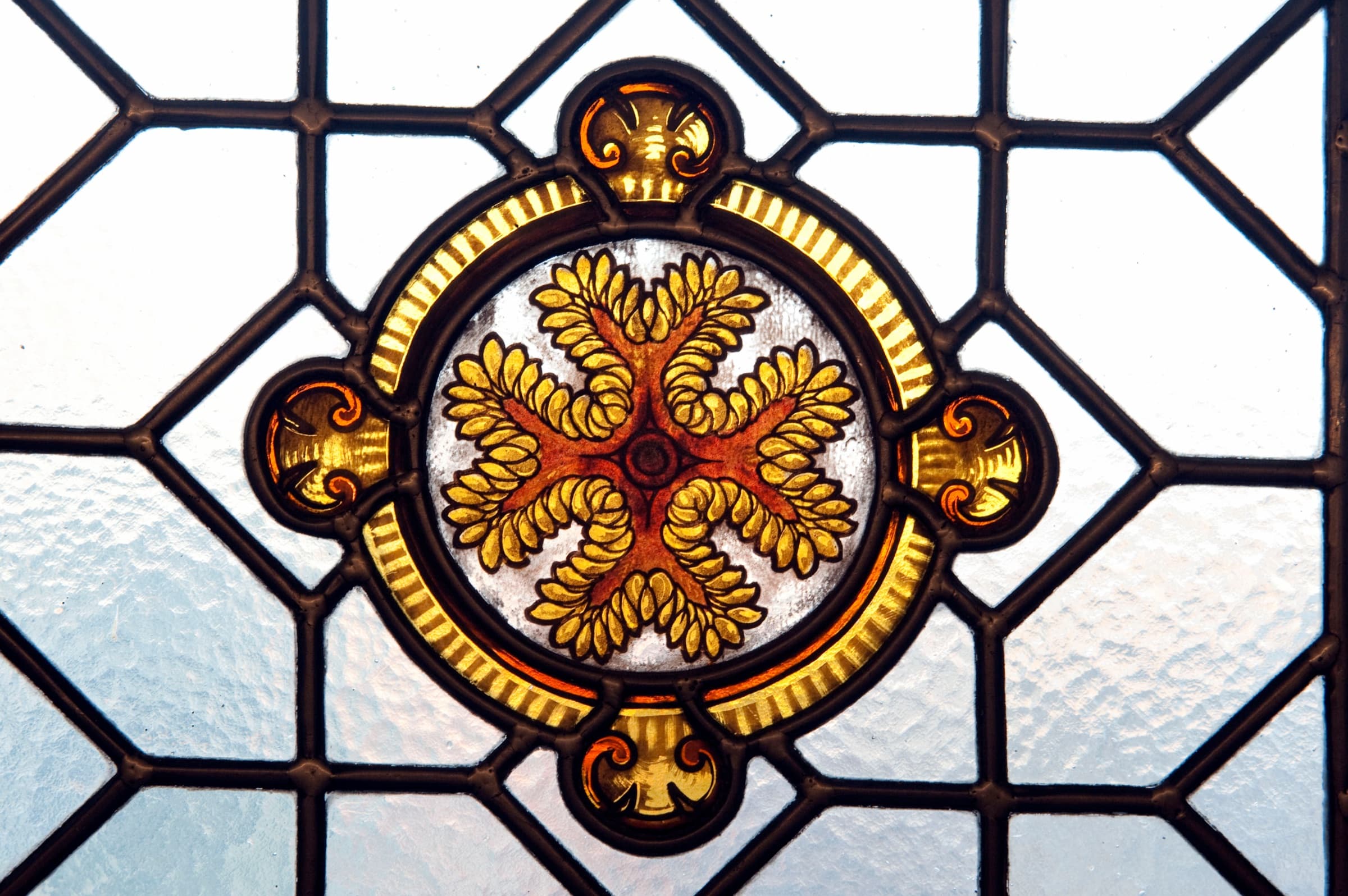 Détail d'un vitrail de la Maison de l'Océan : une rosace de feuillages dorés cernée de plomb
