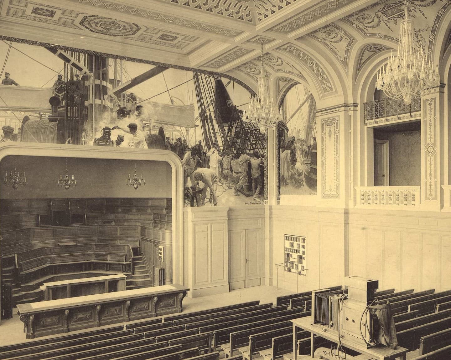 Photographie ancienne du grand amphithéâtre de l’Institut océanographique, ses gradins de bois et ses peintures murales.